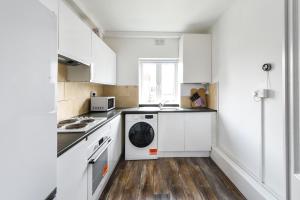 a kitchen with white cabinets and a washing machine at 2BR Hendon Flat - Free Parking & Bus stop outside in Hendon