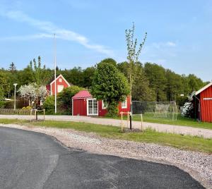 an empty road with a red barn and a fence at Lyckan - Minihus i lantlig miljö in Ulricehamn