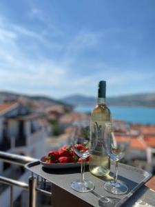 Apartments Proxima في تروغير: طاولة مع صحن من الفواكه وزجاجة من النبيذ