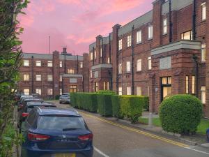 a parking lot with cars parked in front of a brick building at 2BR Hendon Flat - Free Parking & Bus stop outside in Hendon