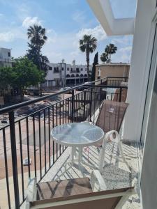a balcony with a table and chairs and palm trees at Almyria Apartments - By IMH Travel & Tours in Paphos