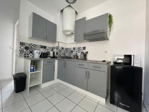 a kitchen with white cabinets and a black refrigerator at Bizanos - 4 pers, wifi, balcon in Bizanos