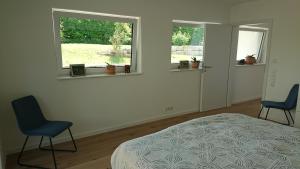 a bedroom with two chairs and a bed and two windows at Ruhezeit in Stockach