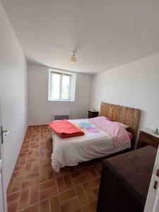 a bedroom with a bed and a brown tile floor at Location à la campagne 