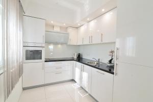 una cocina blanca con armarios blancos y fregadero en Shine Luxury, en Maslenica