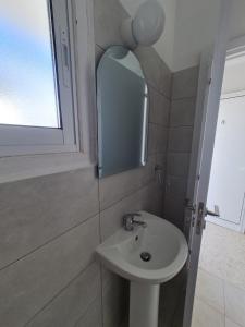 bagno con lavandino e specchio di Almyria Apartments - By IMH Travel & Tours a Paphos