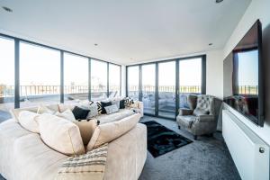 a living room with a large couch and a tv at Luxurious 2-Bedroom Penthouse Apartment with Stunning Glass-Wall Views in Barnsley Town Centre in Barnsley