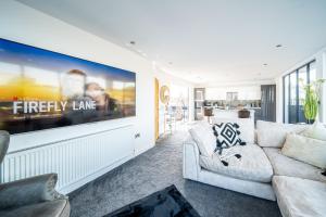 a living room with a white couch and a large tv at Luxurious 2-Bedroom Penthouse Apartment with Stunning Glass-Wall Views in Barnsley Town Centre in Barnsley
