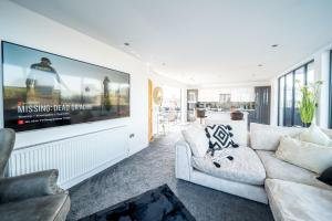 a living room with a white couch and a tv at Luxurious 2-Bedroom Penthouse Apartment with Stunning Glass-Wall Views in Barnsley Town Centre in Barnsley
