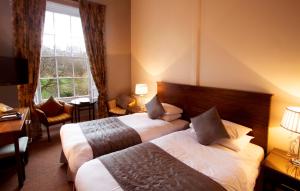 een hotelkamer met 2 bedden en een raam bij Royal Scots Club in Edinburgh