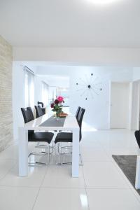 un comedor blanco con una mesa blanca y sillas negras en Shine Luxury, en Maslenica