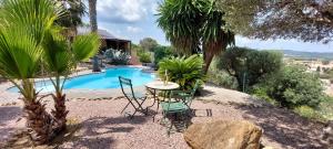 a patio with a table and chairs next to a pool at Beautiful Villa with a stunning view in Roujan