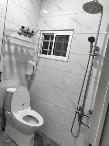 a white bathroom with a toilet and a window at Fangliao Little Swallow Light Hotel in Fangliao