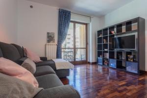 ein Wohnzimmer mit einem Sofa und einem TV in der Unterkunft Bright Apartment near Parco Dora by Wonderful Italy in Turin