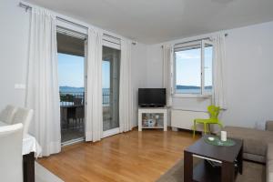 a living room with a couch and a tv and windows at Lila1 Apartments in Zadar