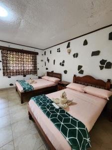 a room with two beds and a wall with rocks at TipTop Hotel, Resto and Delishop in Panglao
