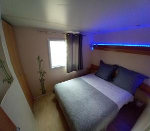 a small bedroom with a bed with a blue light at Mobile home au camping les Tilleuls du Caminel in Sarlat-la-Canéda