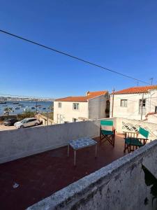 eine Terrasse mit 2 Stühlen und einer Bank an der Wand in der Unterkunft Lisbon Sea and City in Trafaria