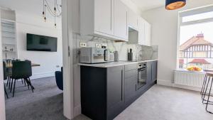 una cocina con armarios blancos y una mesa en una habitación en West Shore Apartment by Seaside Llandudno en Llandudno