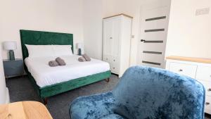 1 dormitorio con 1 cama y 1 silla azul en West Shore Apartment by Seaside Llandudno en Llandudno