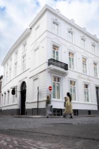 2 personnes marchant devant un bâtiment blanc dans l'établissement Hotel du Théâtre, à Bruges