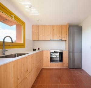 uma cozinha com armários de madeira e um frigorífico de aço inoxidável em Ca la Carolina em Rabós