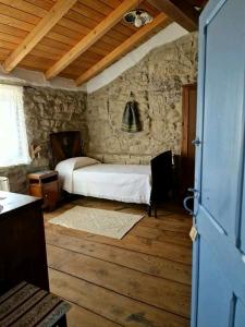 1 dormitorio con cama y pared de piedra en Sa domu de ziu Antoneddu, en Tuili