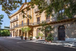 a large yellow building with balconies on a street at Palazzo De Gregorio Apartments in Palermo