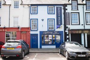 two cars parked in front of a blue and white building at Vanity Ballycastle Diamond 2 bedroom apartment in Ballycastle