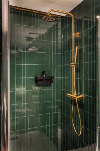 a green tiled bathroom with a shower with a hose at BYPILLOW Twenty in Barcelona