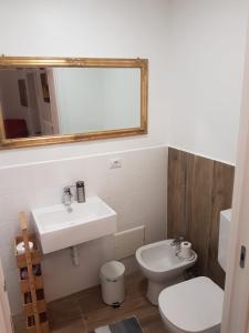ein Badezimmer mit einem Waschbecken, einem WC und einem Spiegel in der Unterkunft GusterHouse in Ivrea