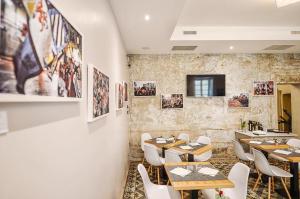ein Restaurant mit Tischen, Stühlen und Bildern an der Wand in der Unterkunft GusterHouse in Ivrea