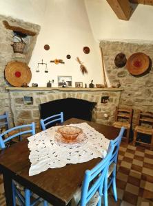 een eetkamer met een tafel met stoelen en een open haard bij Sa domu de ziu Antoneddu in Tuili