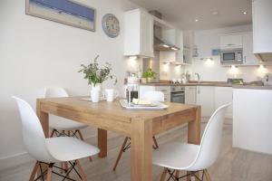 a kitchen with a wooden table and white chairs at Fistral View, Pentire in Newquay