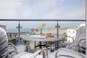a table with two glasses of wine on a balcony at Fistral View, Pentire in Newquay