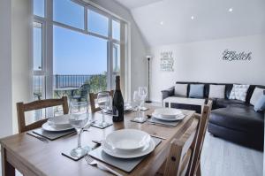 a dining room with a table with a bottle of wine at Campbell - 2 Bedroom Apartment - Pendine in Pendine