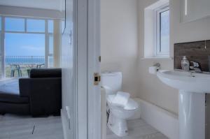 a bathroom with a toilet and a sink and a window at Campbell - 2 Bedroom Apartment - Pendine in Pendine