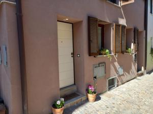 a building with a white door and two potted plants at Antico Vicolo - Appartamento Giulia in Vercelli