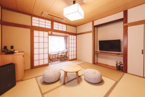 a living room with a table and two chairs and a television at 蓼科BASE kitchen,spa&hotel in Chino