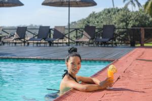 a woman in a swimming pool holding a drink at San Lameer Villa 2908 - 3 Bedroom Superior - 6 pax - San Lameer Rentals Agency in Southbroom