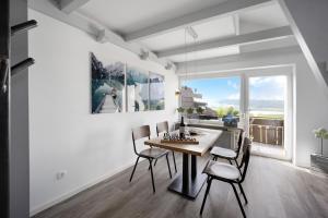 een eetkamer met een tafel en stoelen en een groot raam bij Loft mit Seeblick und Innenpool 