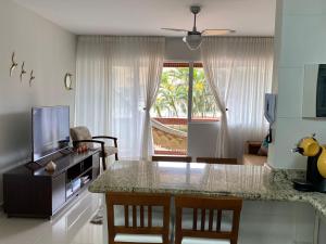 a kitchen and living room with a table and a television at Apto todo equipado em Caiobá há 50m do mar in Matinhos