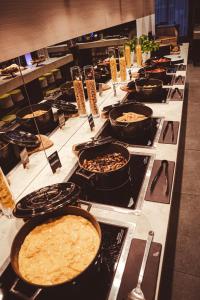a buffet line of casseroles in pots and pans at Holiday Inn Dąbrowa Górnicza-Katowice, an IHG Hotel in Dąbrowa Górnicza