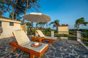 two chairs and an umbrella on a patio at Villa Pefki in Agalás