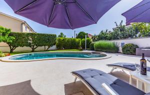 einen Pool mit einem Sonnenschirm, 2 Stühlen und einem Tisch in der Unterkunft Villa Jasmine with swimming pool in Pula