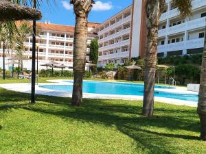 a hotel with a swimming pool and palm trees at Manilva Playa in Manilva