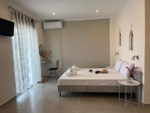 a white bedroom with a bed and a television at House Kohili in Nea Vrasna
