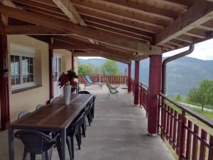 eine Terrasse mit einem Holztisch und Stühlen auf einer Veranda in der Unterkunft Gîtes BEL'M in La Bresse