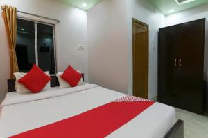 a bedroom with a large bed with red pillows at OYO Flagship 67063 Roy Villa Resort in Baharampur