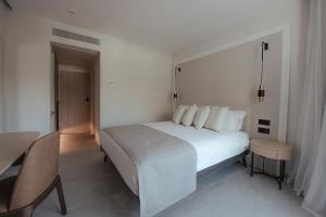 a bedroom with a large white bed and a table at Atlantica Bay - Adults Only in Limassol